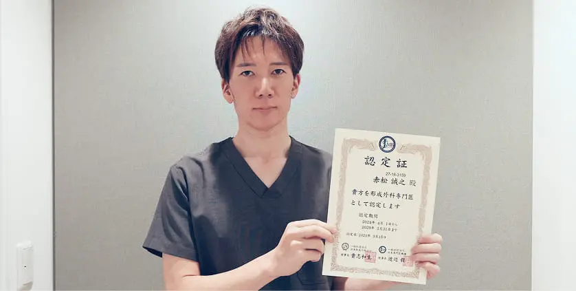 ベルモナクリニック院長 赤松誠之が、認定証を両手で持って正面を向いて立っている。