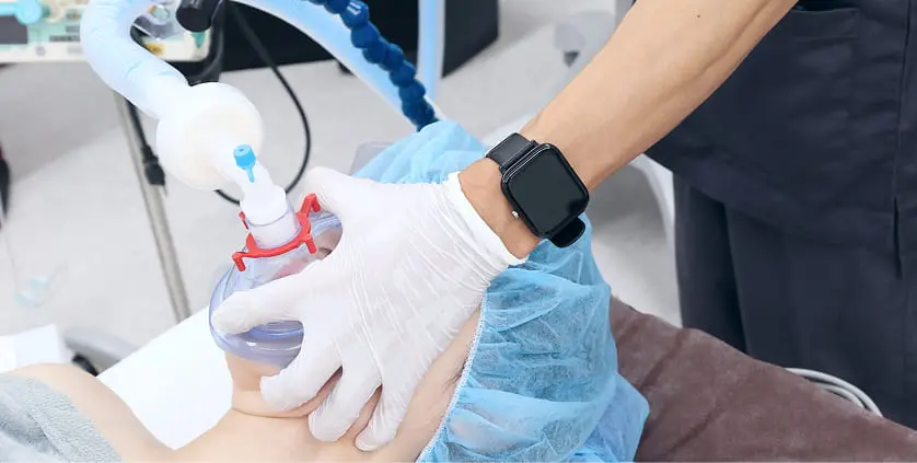 医療スタッフが手袋を着用し、患者の顔に酸素マスクをあてている