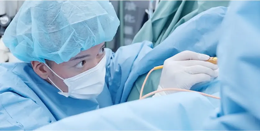 手術着とキャップ、マスクを着用した医師が、真剣な表情で手術を行っている。