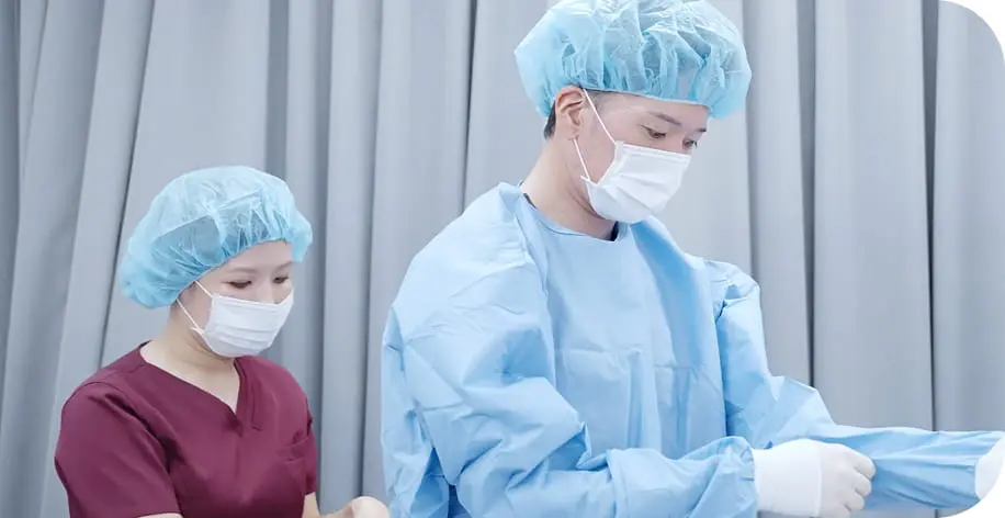 青い手術着とキャップを着用した医療スタッフが手術の準備をしている